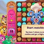 カラフルなクッキーとキャラクターが並ぶゲームの画面で、中央にコック帽をかぶった青いネズミのキャラクターがいる。